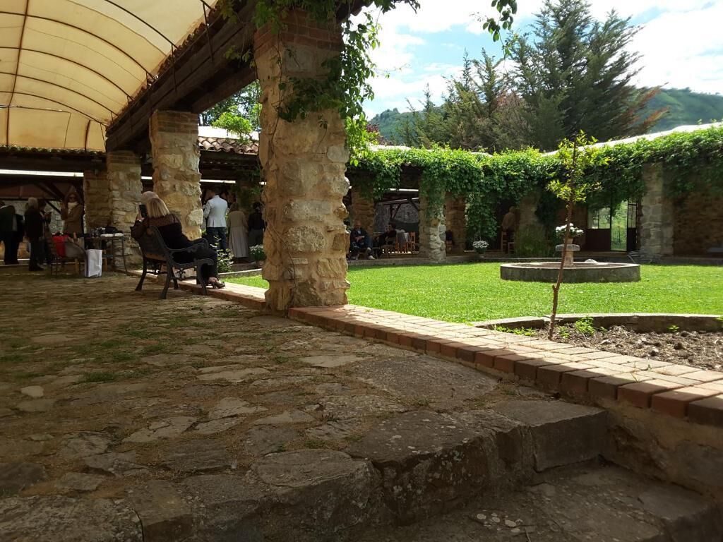 An outdoor courtyard with stone flooring, a covered seating area, and a small fountain.