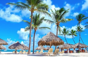 A beach with thatched umbrellas and lounge chairs. - Los Corales Beach Village - Your private paradise - 2BR ground floor - LT#VR (Punta Cana)