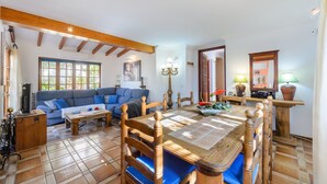 A cozy living room with a blue sofa, wooden dining table, and a tiled floor.