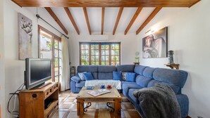 A cozy living room with a blue sofa, wooden coffee table, and a television.