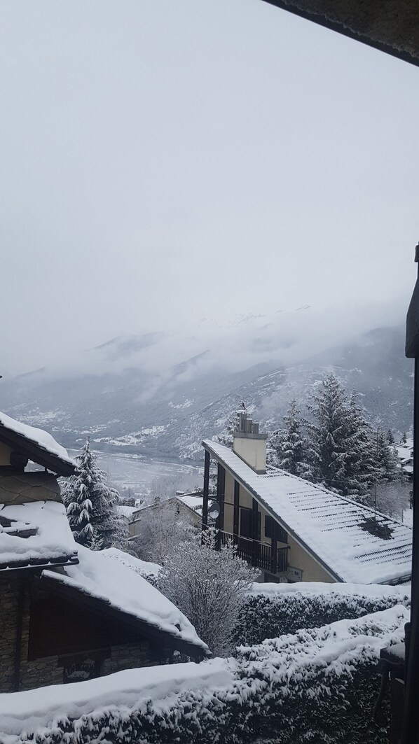 Un paisaje montañoso nevado con una casa con techo inclinado y chimenea.