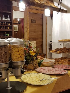 A buffet table with various food items including cereal, flowers, and pastries. - Hotel Martin (Sauze d'Oulx)