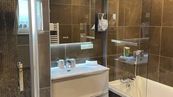 A modern bathroom with a glass-enclosed shower, a white sink with a mirror above, and a large mirror on the wall.