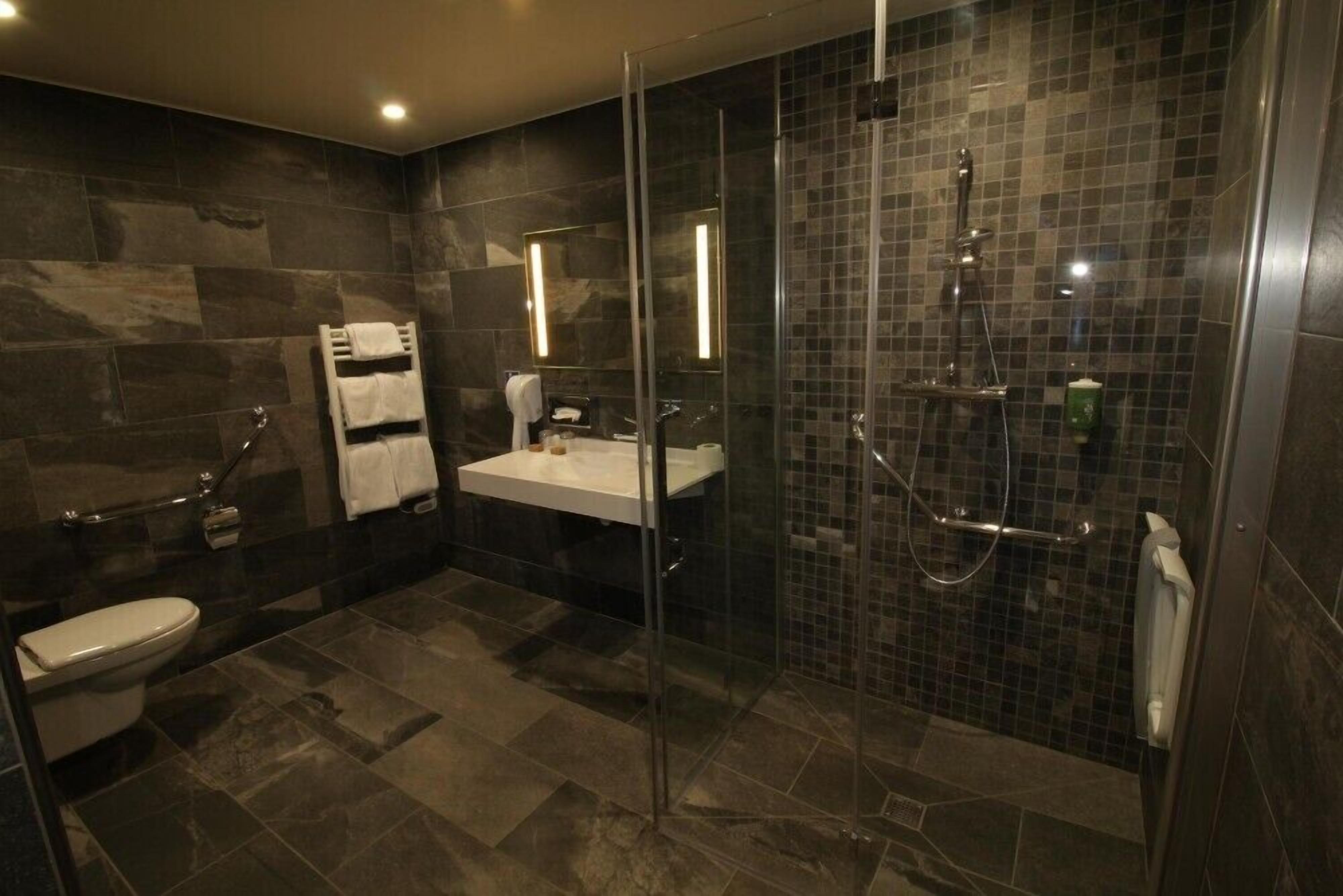 Un baño moderno con ducha acristalada, lavabo blanco y retrete.
