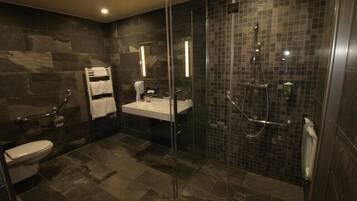 Un baño moderno con ducha acristalada, lavabo blanco y retrete.