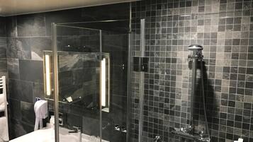 A modern bathroom with a glass-enclosed shower, a white sink, and a large mirror.
