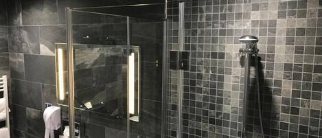 A modern bathroom with a glass-enclosed shower, a white sink, and a large mirror.