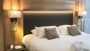 Een hotelkamer met een groot bed, twee bedlampen, een telefoon en een radiator.