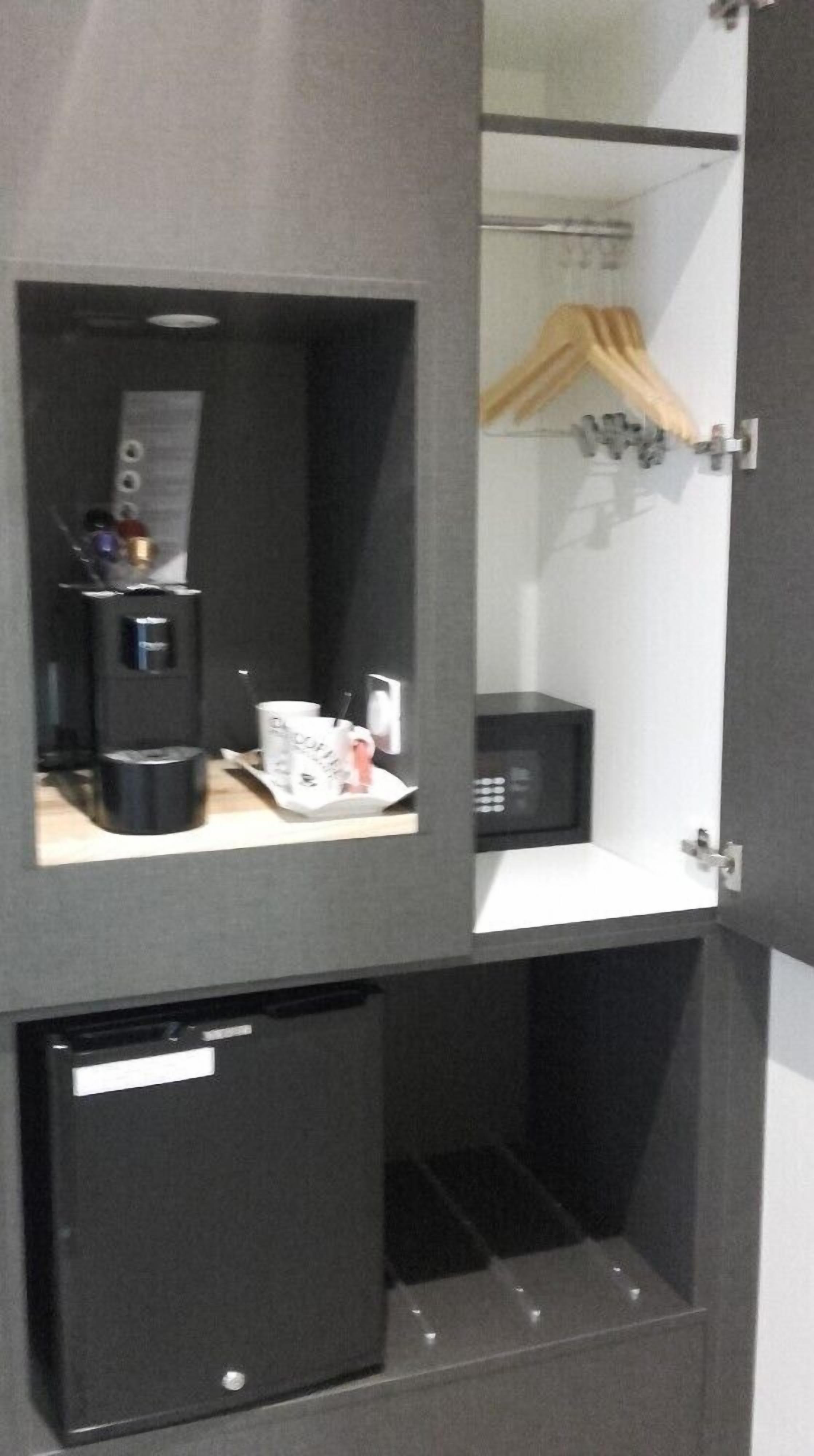 Una habitación compacta con kitchenette que incluye cafetera, microondas y un refrigerador pequeño.