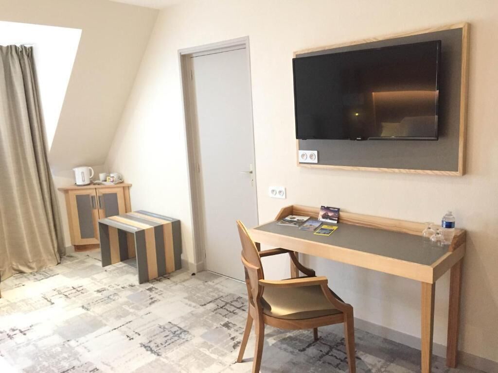 Een kleine kamer met een bureau, stoel en een aan de muur bevestigde televisie.
