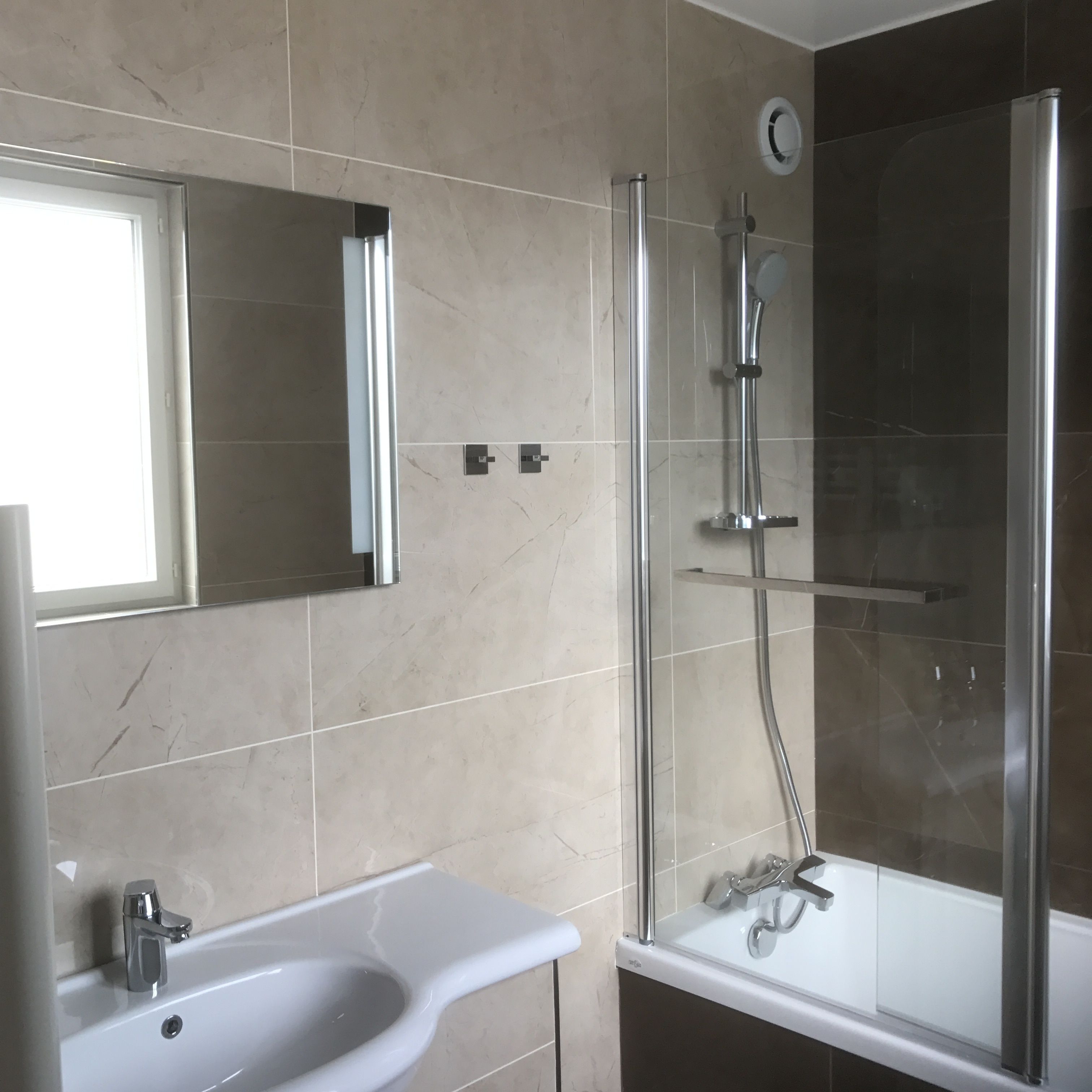 A modern bathroom with a glass-enclosed shower, a white sink, and a mirror above the sink.