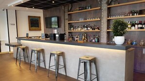 Een bar met een toonbank, krukken, flessen op planken en een televisie.