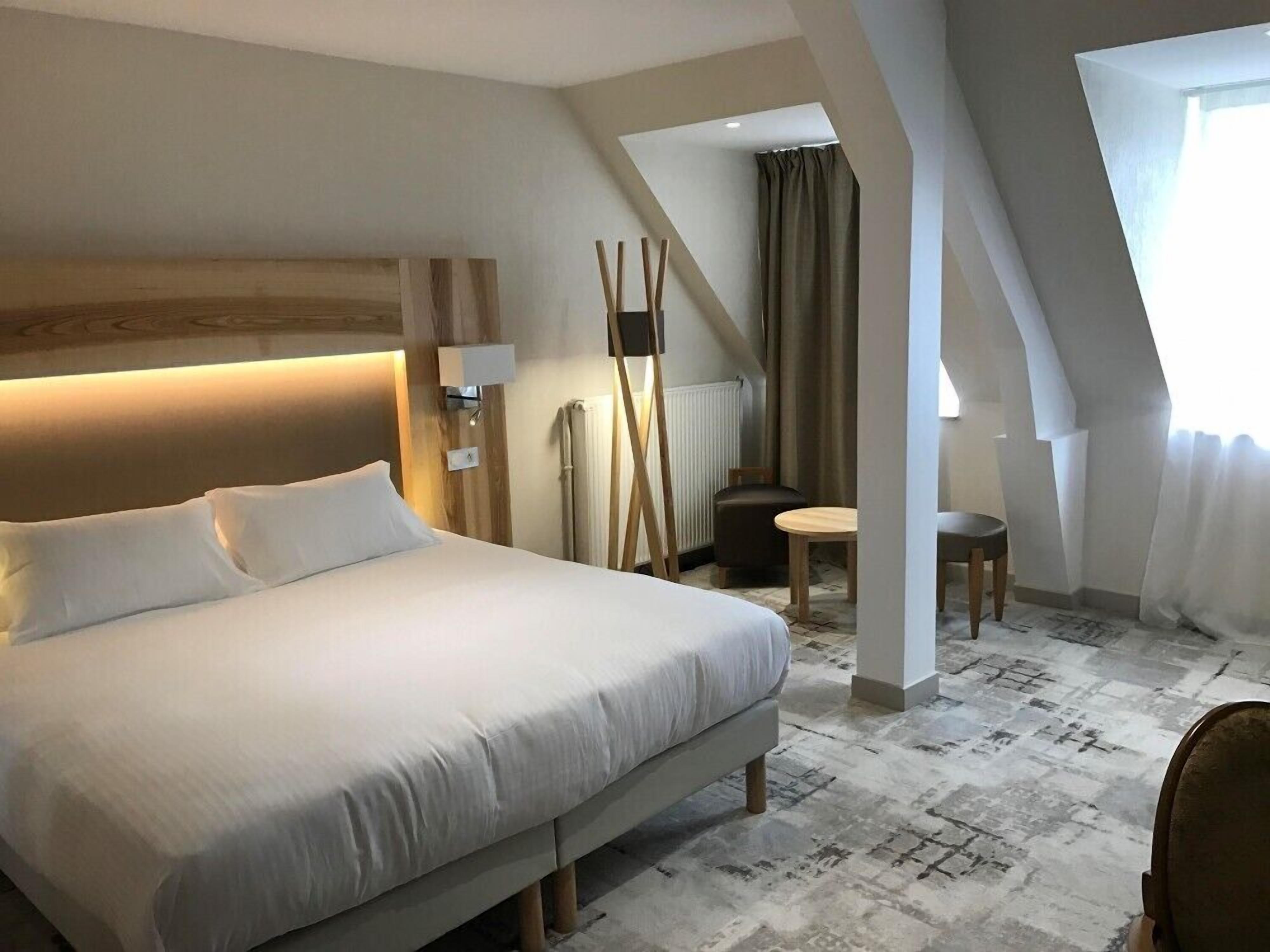 A modern hotel room with a large bed, a small table, and a chair.