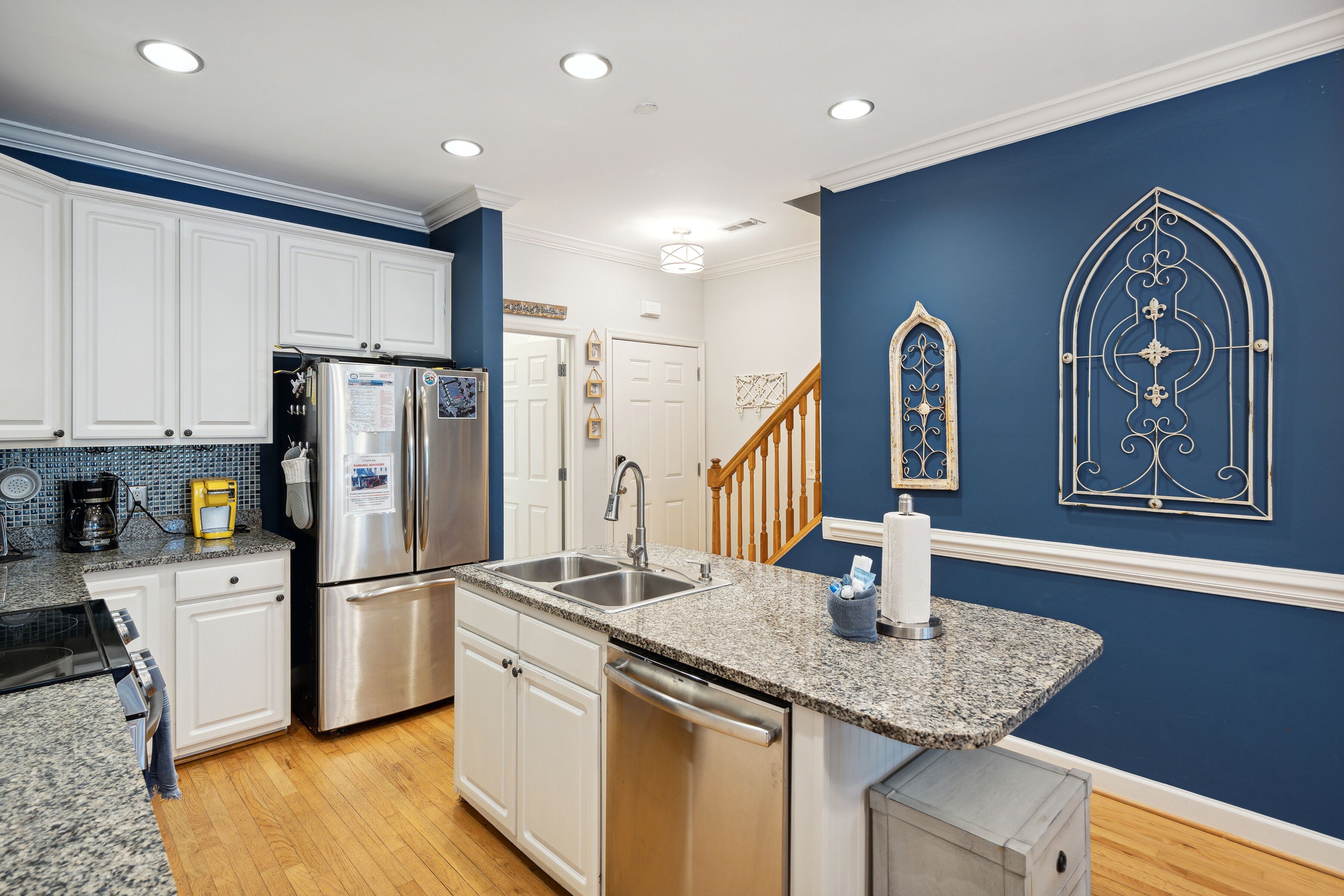 A kitchen with white cabinets, stainless steel appliances, granite countertops, and blue walls.