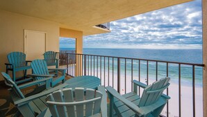 Un balcón con sillas Adirondack azules, una mesa y vistas al océano.