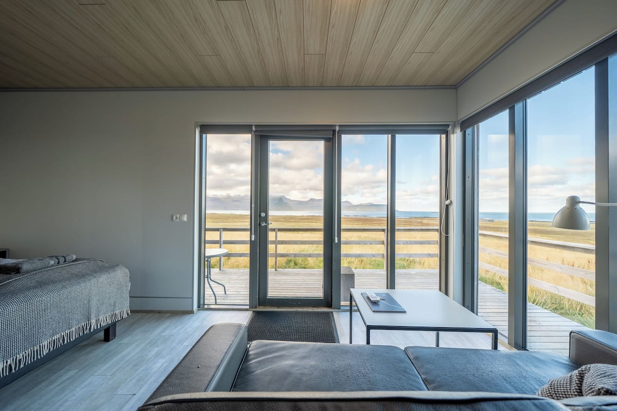 Une chambre moderne dotée d’une grande porte-fenêtre coulissante donnant sur une terrasse avec vue sur la plage.