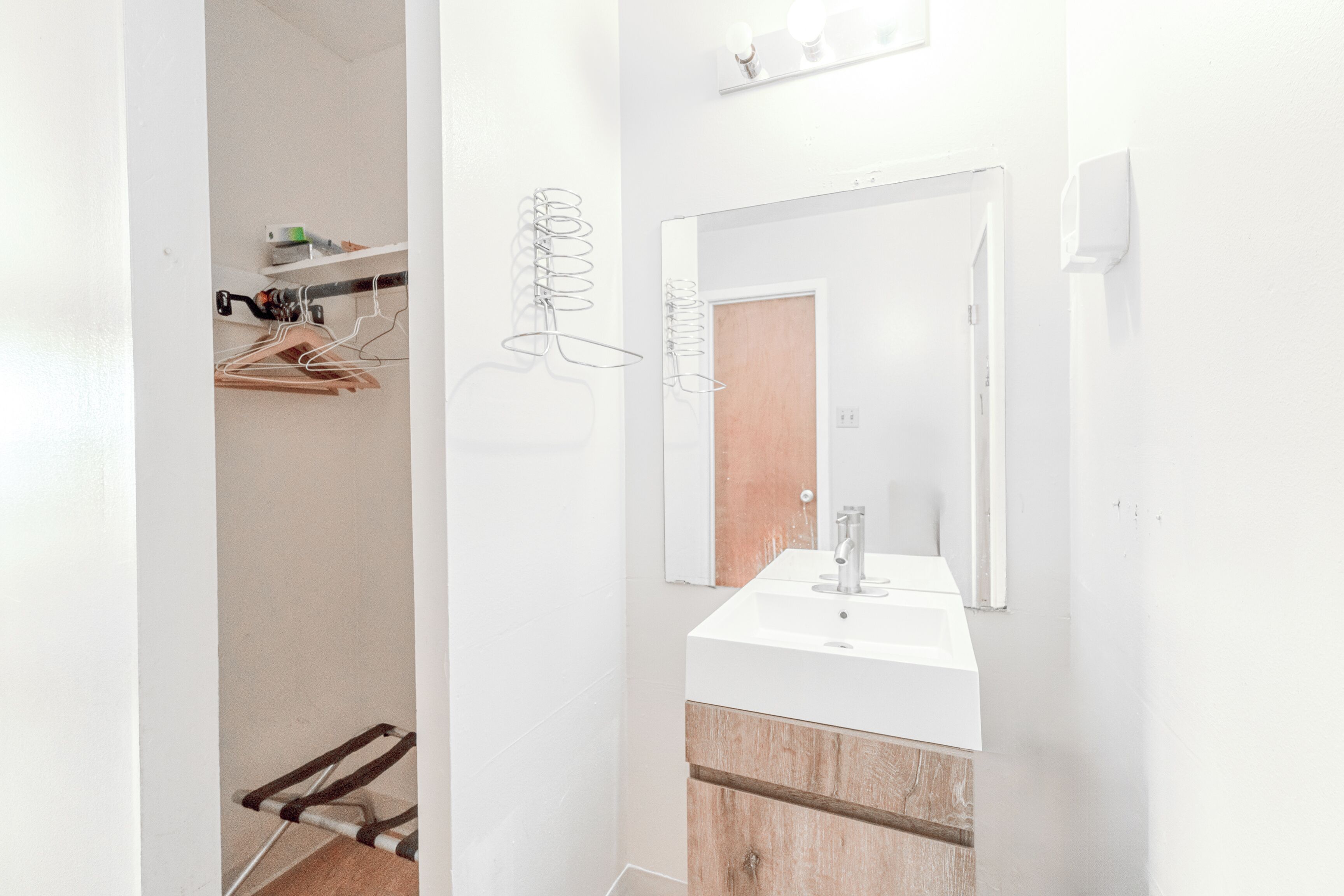 A modern bathroom with a white sink, wooden vanity, and a mirror above it.