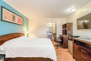 Une chambre d’hôtel avec un lit, un bureau, une chaise et un miroir.