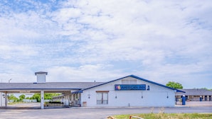 A motel with a covered parking area and a sign reading "AMERICAN INN." - American Inn by OYO Colorado City I-20 (Colorado City)