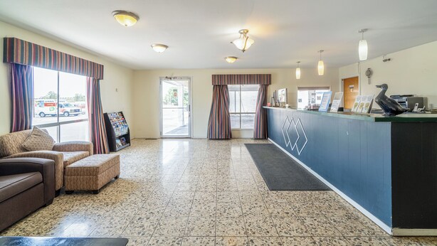 A reception area with a counter, seating, and a view of the outside. - American Inn by OYO Colorado City I-20 (Colorado City)