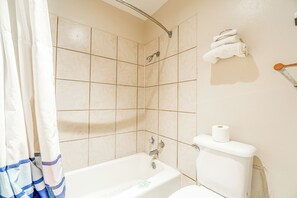 Une salle de bain avec une baignoire, des toilettes et un rideau de douche.