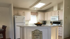 A kitchen with a central island, white cabinets, a microwave, and a coffee maker.
