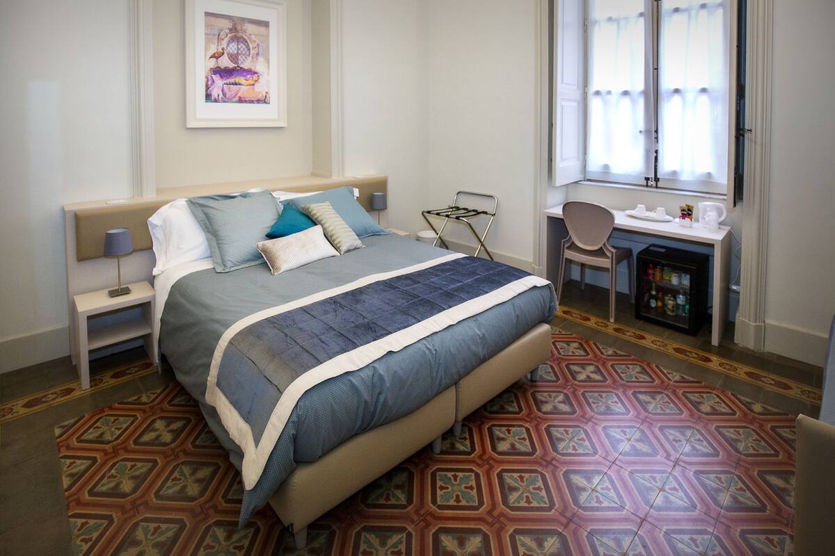 Una habitación de hotel ordenada con cama, escritorio y silla.