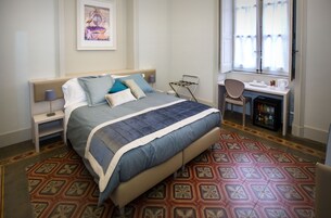 Una habitación de hotel ordenada con cama, escritorio y silla.