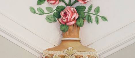 A wall-mounted decorative vase with pink roses and green leaves.