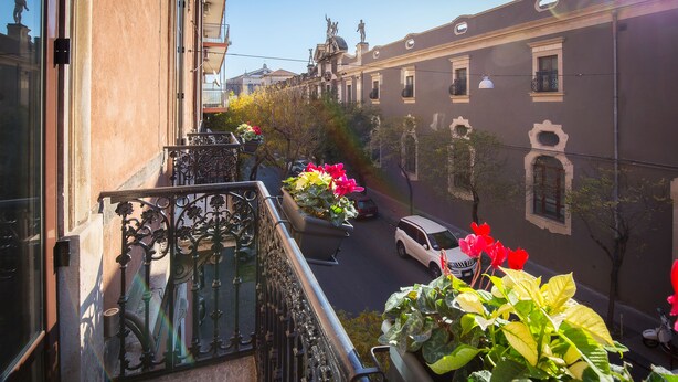 Een balkon met smeedijzeren hekwerk en bloempotten.