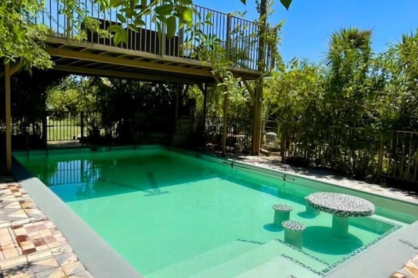 Una piscina techada, una piscina al aire libre, sombrillas