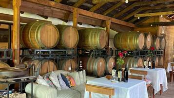 Un interior rústico con barriles de madera, un sofá y mesas dispuestas para comer.