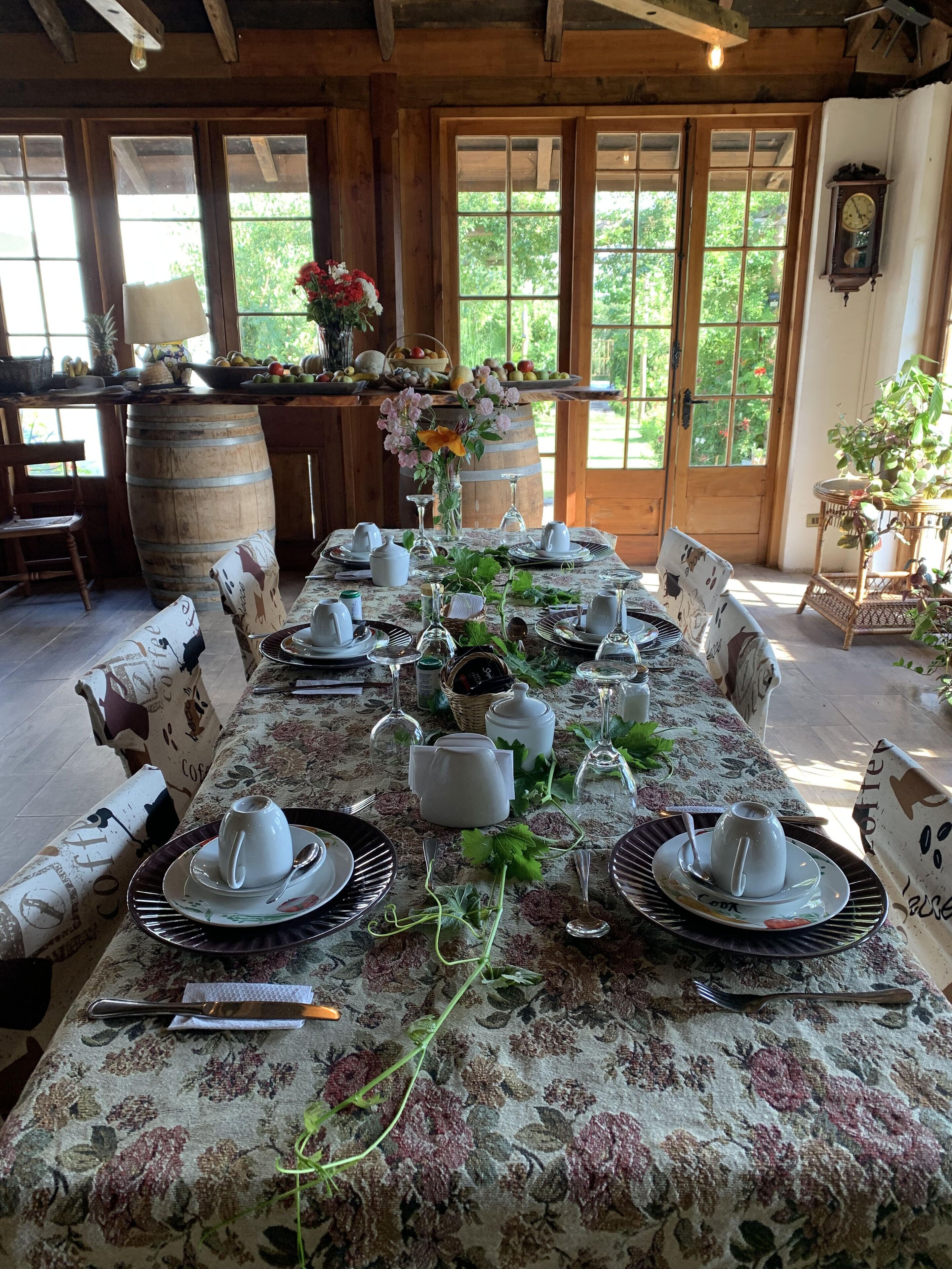 A dining table set for a meal with floral tablecloth, white plates, and silverware.