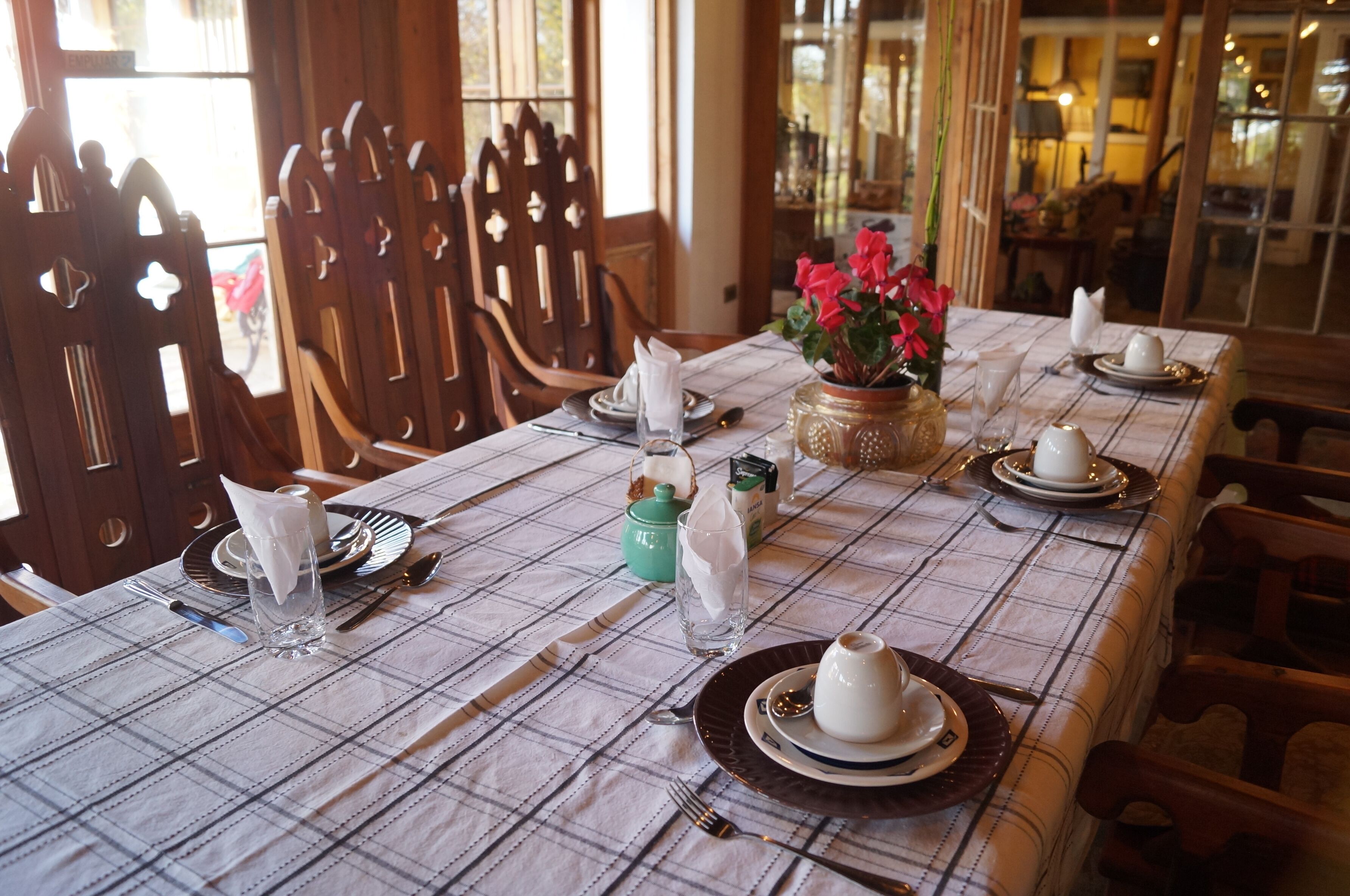 A dining table set with plates, glasses, and a vase of flowers.