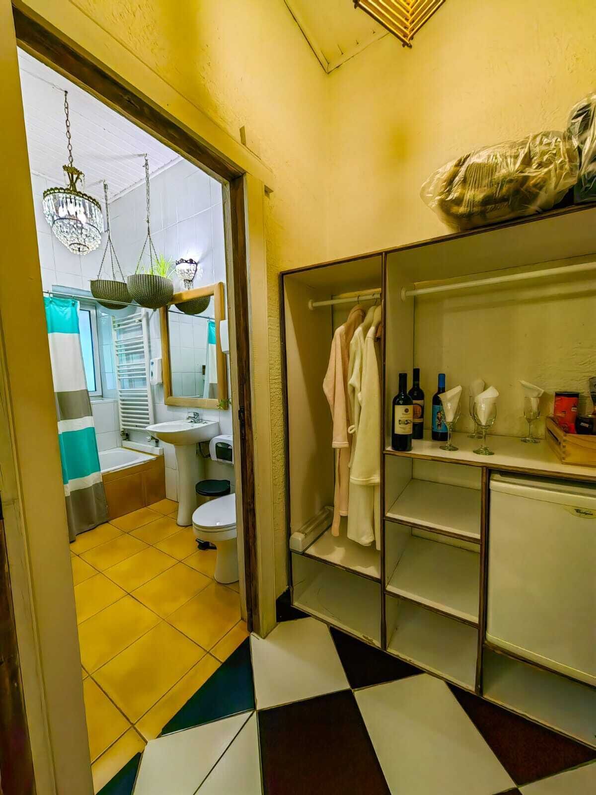 A bathroom with a sink, toilet, and shower area. There is a mirror above the sink and a chandelier hanging from the ceiling.