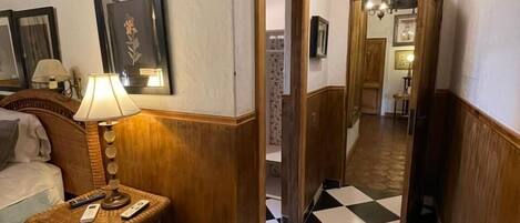 Ein Hotelkorridor mit Schachbrettfußboden, einer Lampe und gerahmten Bildern an den Wänden.