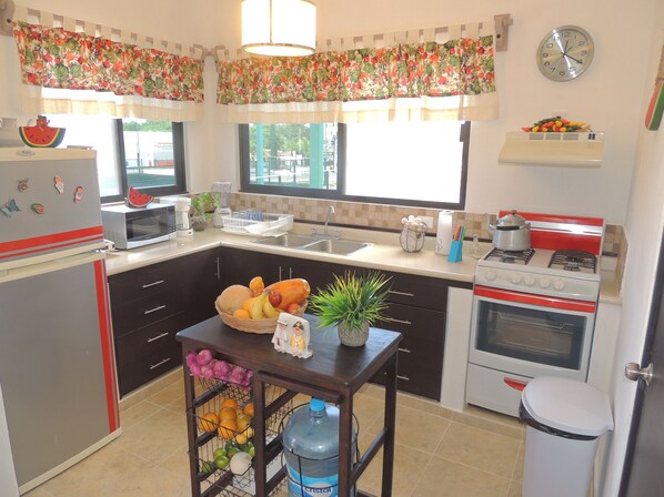 A kitchen with a refrigerator, microwave, sink, stove, and a water dispenser.