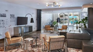 A modern hotel lobby with seating areas, a flat-screen TV, and a large window offering a view of the city. - Fairfield Inn & Suites by Marriott Dallas Downtown (Dallas)