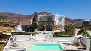 A modern villa with a pool, outdoor seating, and a mountain backdrop. - Maison Simone, a great escape experience!! (Αγ. Σώστης)