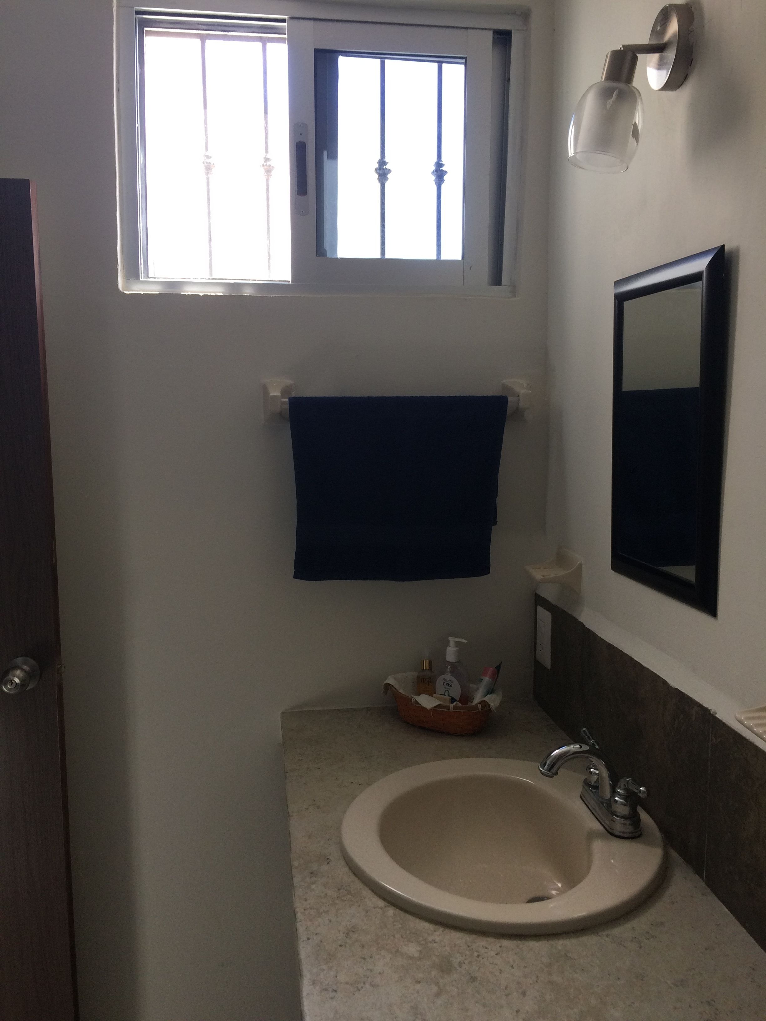 A bathroom with a sink, a mirror, a towel rack, and a window.