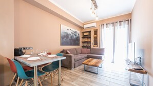A modern living room with a dining area, a sofa, a coffee table, and a TV. - Stylish Luxury Apartment near Acropolis at Neos Kosmos metro station  (Neos kosmos)