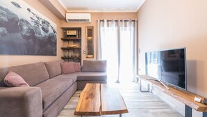 A modern living room with a sectional sofa, a wooden coffee table, a flat-screen TV, and a large window with curtains. - Stylish Luxury Apartment near Acropolis at Neos Kosmos metro station  (Neos kosmos)