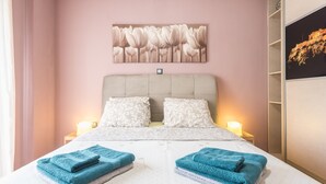 A bedroom with a bed, two pillows, a headboard, a wall-mounted artwork, and a nightstand with a lamp. - Stylish Luxury Apartment near Acropolis at Neos Kosmos metro station  (Neos kosmos)