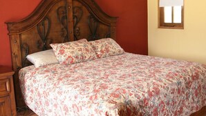 Een bed met een bloemenbedekking, een houten hoofdbord en een nachtkastje met een lade.