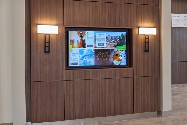 A digital display wall with various advertisements and information.