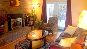 A cozy living room with a fireplace, a floral armchair, a sofa, and a round coffee table. - Los Alamos Flats (Los Alamos)
