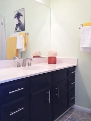 A modern bathroom with a large mirror, a double sink, and dark cabinetry. - Los Alamos Flats (Los Alamos)