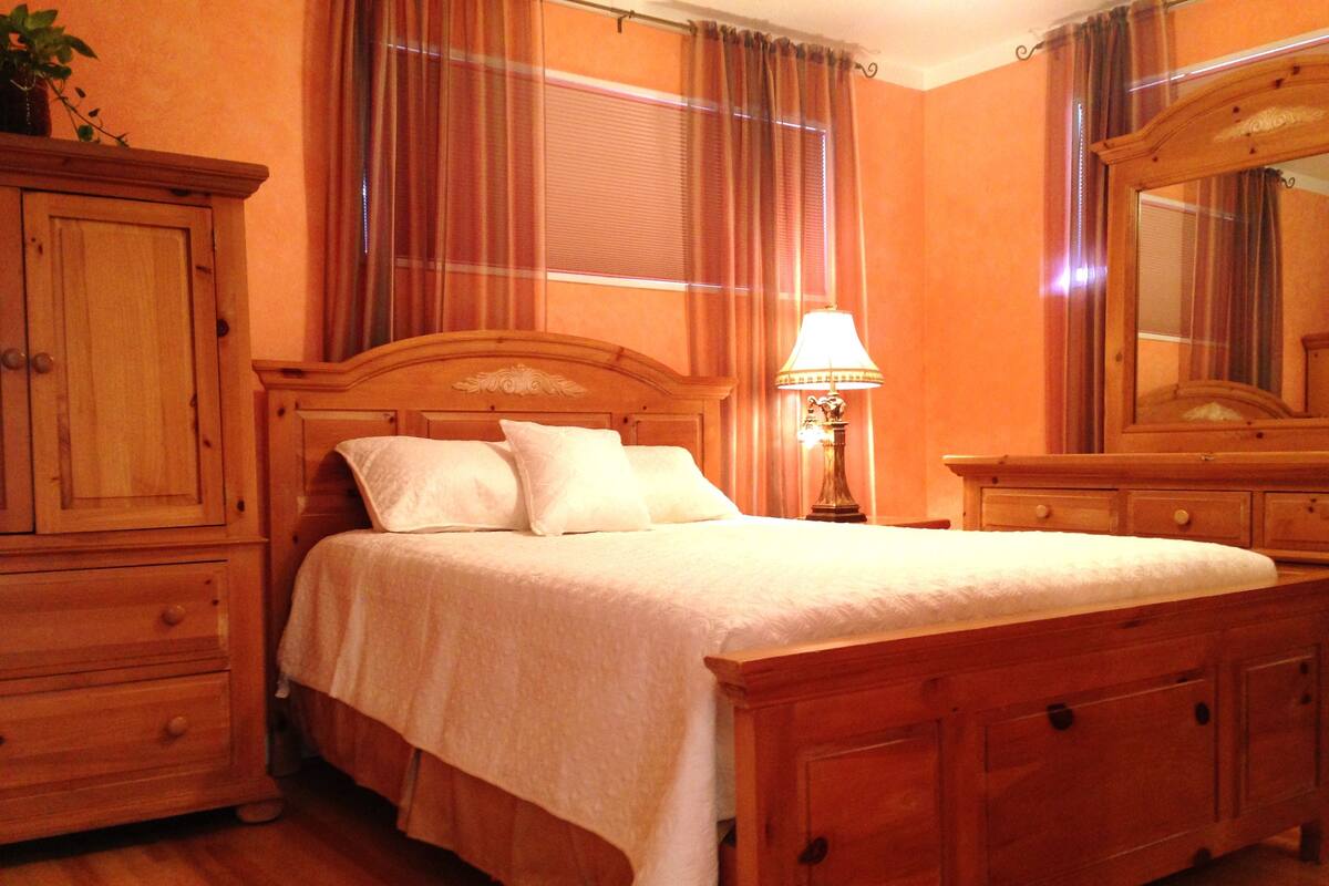 A wooden bed with a headboard, a bedside table with a lamp, and a mirror on the wall.