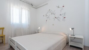 Ein Schlafzimmer mit einem Bett, zwei Nachttischen, einem Sessel und einer Wand mit Vogelmotiven.