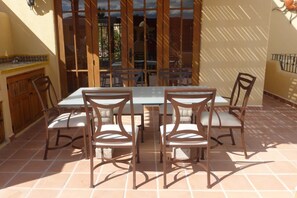 A patio with a table and chairs, a wooden fence, and a tiled floor.